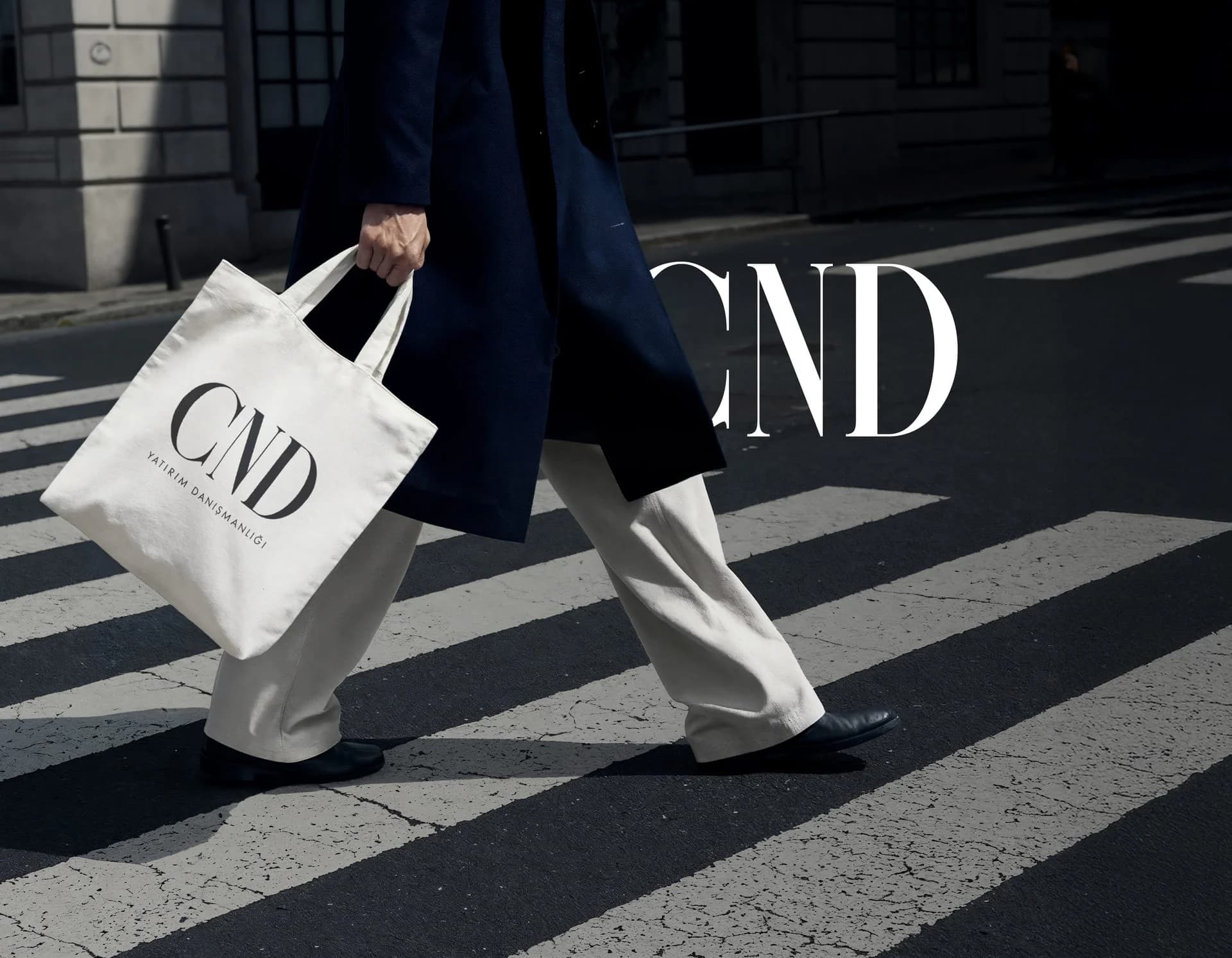 CND tote bag carried across a pedestrian crossing, with the CND logo