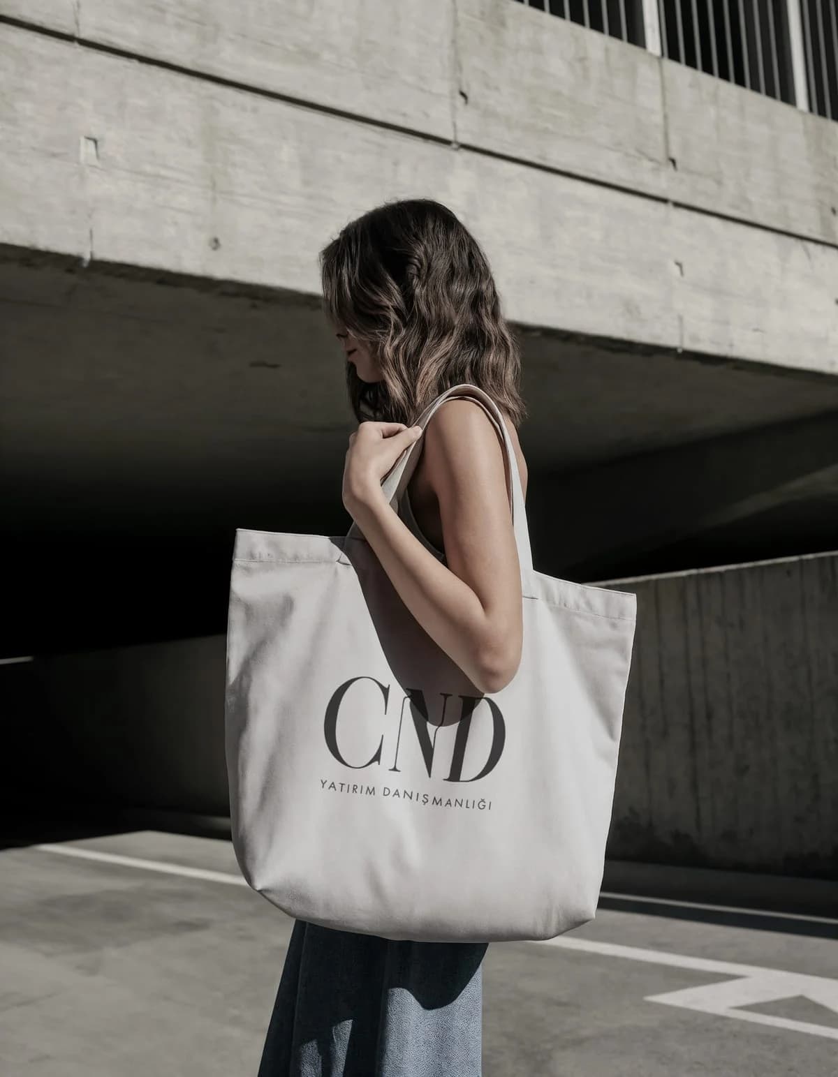 CND tote bag on a shoulder in front of a concrete building