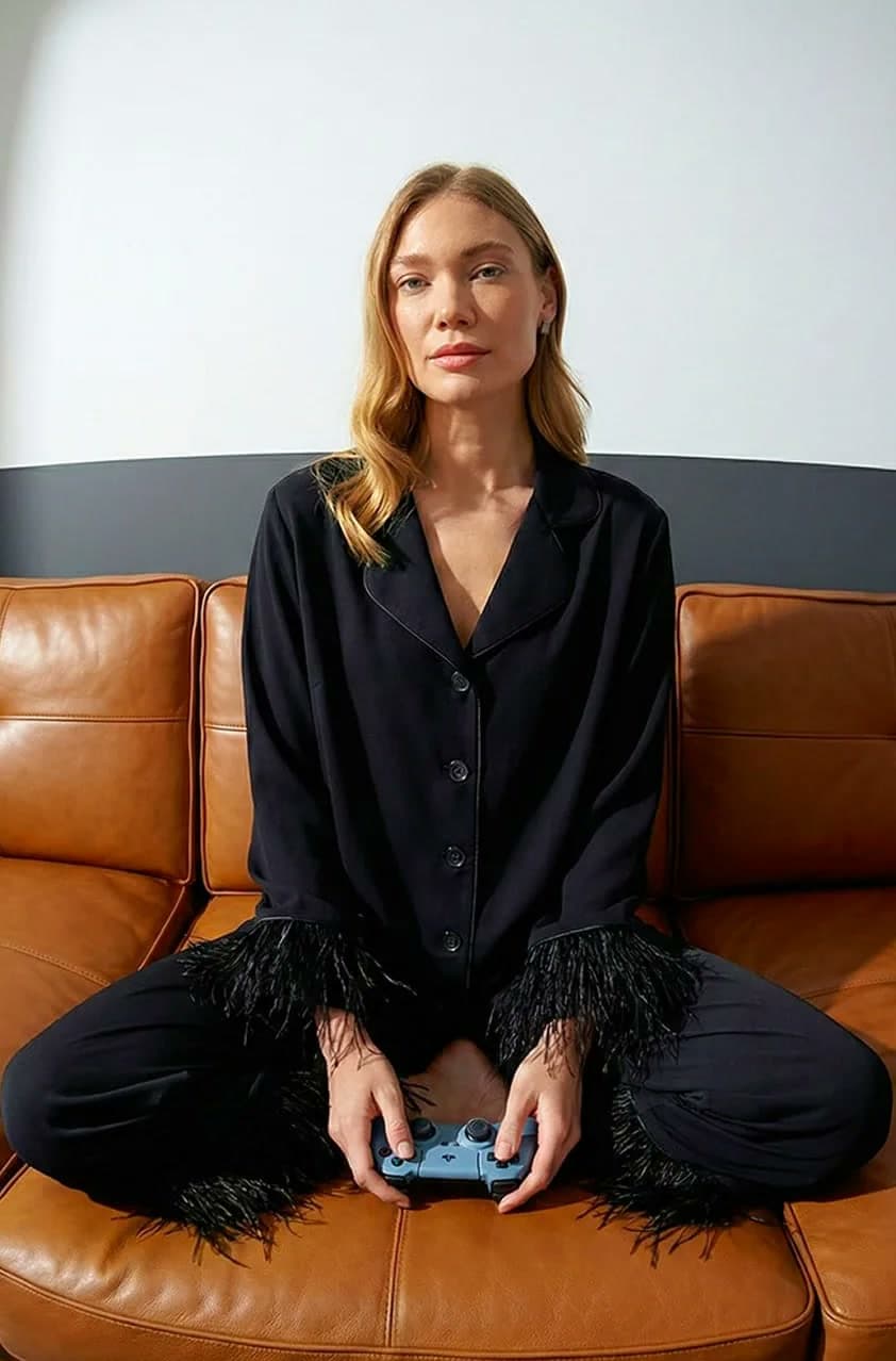 AI model in a black feather-trimmed set, on a leather sofa